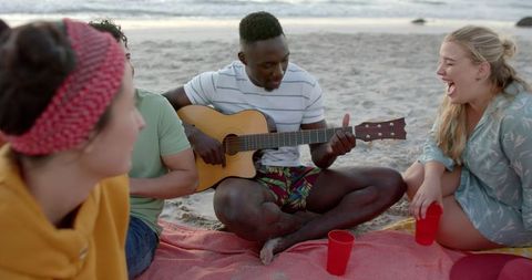 Friends Enjoying Beach Party with Guitar at Sunset