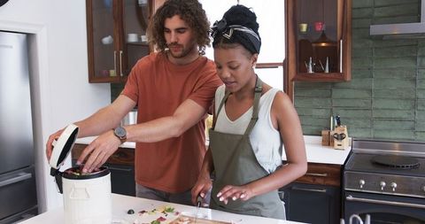 Couple Composting Food Waste in Modern Eco-Friendly Kitchen