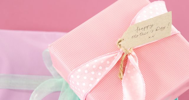 A pink and white striped gift with a tag reading Happy Mother's Day suggests a present for a special occasion, with copy space. Its pastel tones and elegant presentation make it ideal for expressing appreciation on Mother's Day.