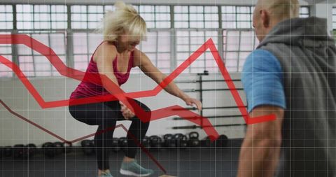 Woman performing box jump with trainer in modern gym
