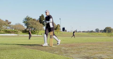 Male Cricketer Running Past Stumps in Intense Match