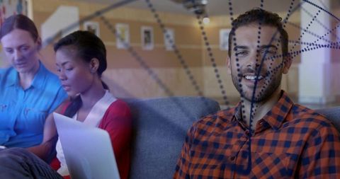 Smiling bearded man collaborating on laptop while sitting on couch in modern coworking lounge
