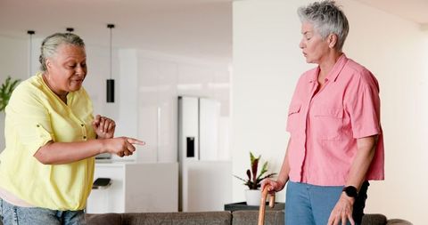 Smiling leisurely multiracial lesbian couple communicating at home