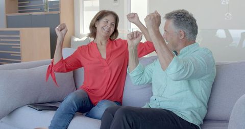 Joyful Senior Couple Relaxing Laughing on Sofa at Home