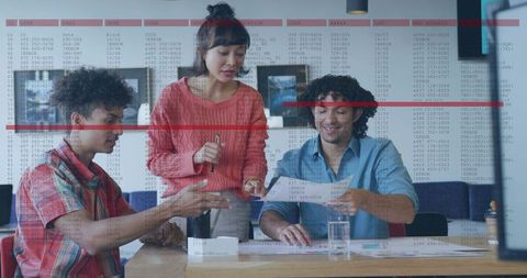 Designer guiding team on mockup while collaborating at studio table, brainstorming ideas