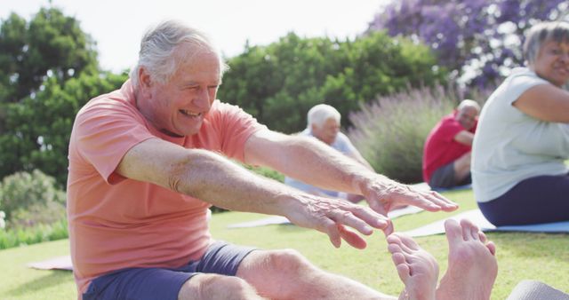 Happy caucasian man touching toes with diverse group of seniors exercising in garden, slow motion. Healthy, active senior lifestyle.