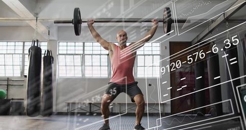 Mid-adult man lifting loaded barbell overhead with AR readouts in industrial gym