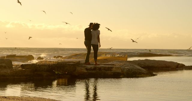 Romantic diverse couple holding hands and standing on pier at sunrise, copy space. Summer, vacation, romance, love, relationship, free time and lifestyle, unaltered.