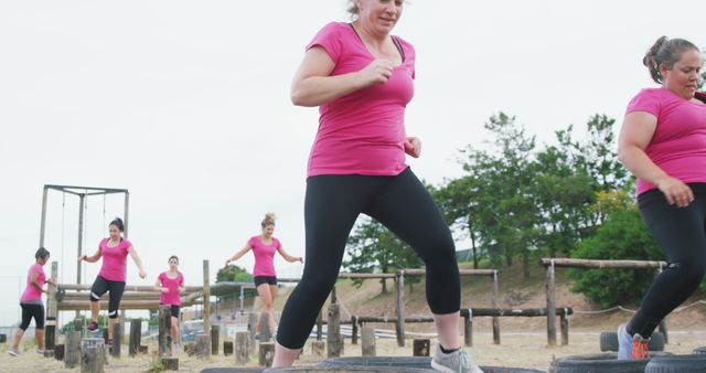 Group of women working out at an outdoor fitness boot camp, focusing on tire exercises, demonstrates teamwork and dedication to fitness. Perfect for use in fitness promotions, health and wellness campaigns, or community building initiatives.