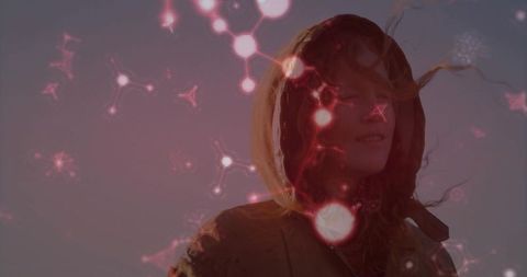 Woman in hooded jacket with molecular light effects against dusk sky
