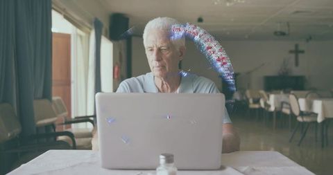Senior man working on laptop in church hall dining room, digital connection for seniors