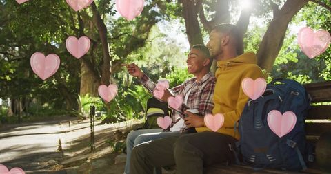 Romantic male couple relaxing on park bench with hearts