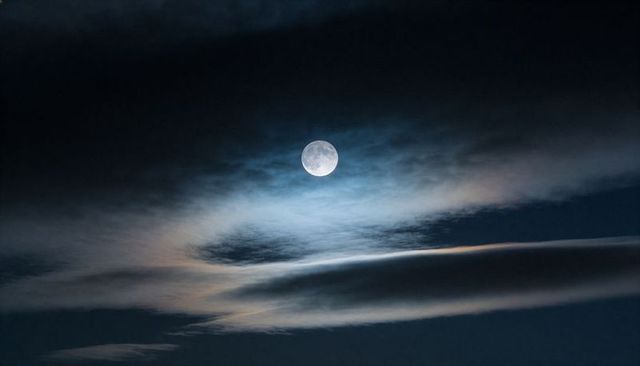 Full Moon Casting Iridescent Blue Halo Over Layered Clouds Night Sky Tranquil Lunar Scene