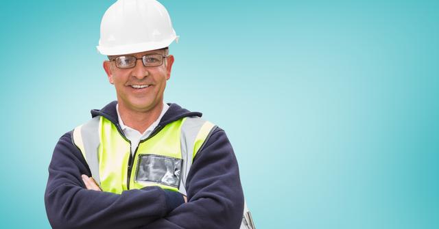 Portrait of architect in hardhat and spectacles standing with arms crossed against blue background