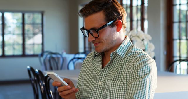 Young Man Using Smartphone in Sunlit Room - Download Free Stock Images Pikwizard.com