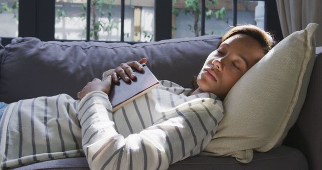 African american woman lying on sofa, holding book and sleeping - Download Free Stock Photos Pikwizard.com