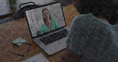 Remote video meeting at home workspace showing man watching woman on laptop screen, glasses on desk