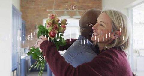 Mature couple embracing while woman holds bouquet in sunlit cozy kitchen with cabinets