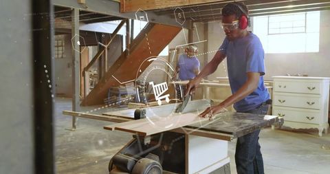 Carpenter cutting plywood on table saw wearing safety goggles and ear protection