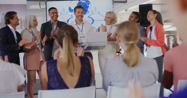 A young businessman receives applause from a diverse audience and colleagues at a presentation. - Download Free Stock Photos Pikwizard.com