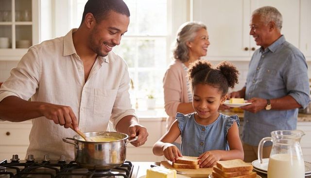 Family breakfast father stirring daughter making sandwiches grandparents smiling sunlit kitchen