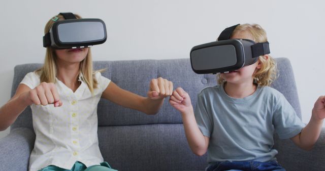 Two children sitting on a sofa wearing VR headsets, engaged in a virtual reality experience. This image can be used to depict modern technology, youth engagement with digital entertainment, or family leisure activities. Suitable for tech blogs, educational articles about VR, and advertisements for gaming products.