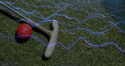 Red dimpled golf ball and putter resting on putting green with neon blue light trails