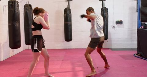 Diverse sparring partners trading light jabs on red mat with pink hand wraps