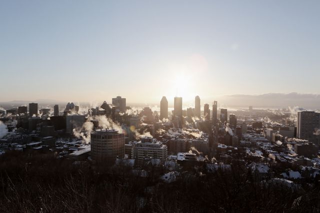 Beautiful sunrise scene over a city during winter with steam rising from buildings, perfect for articles about urban living in cold climates, heating and energy usage, winter weather, morning routines of city dwellers, or promotional material for city tourism.