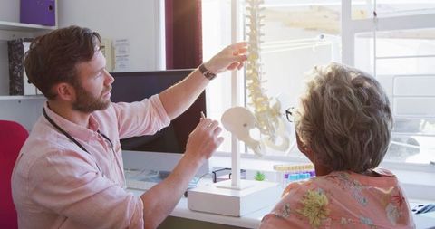 Doctor explaining spine to senior male patient in medical office