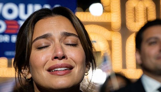 Emotional woman crying during campaign rally under marquee lights and bokeh crowd