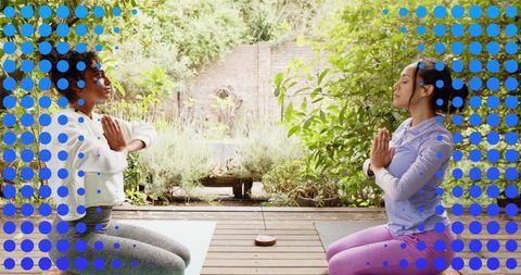Two Women Kneeling Practicing Yoga on Garden Deck with Blue Dot Overlay for Mindfulness
