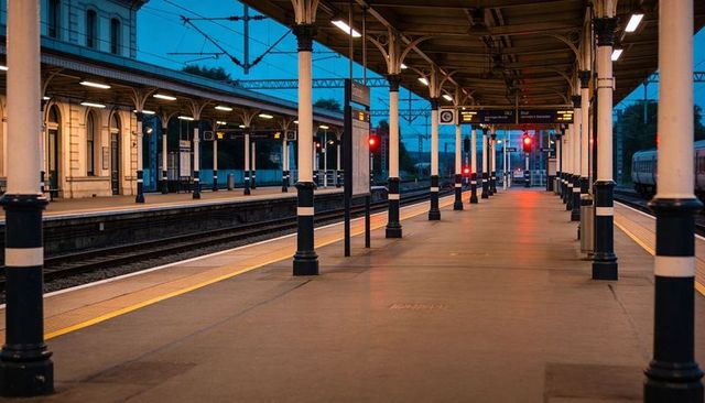Empty Twilight Railway Platform with Symmetrical Iron Columns, Yellow Tactile Strip, Red Signals