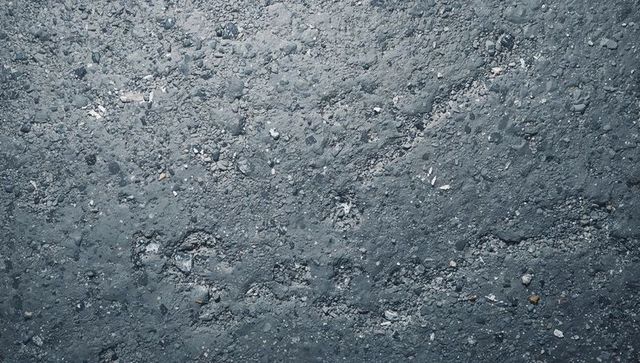 Displaying rough asphalt texture with loose gravel, pebbles and granular mineral flecks