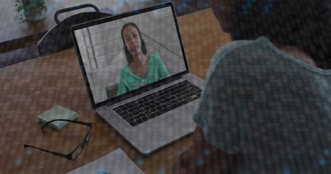 Female professional appearing on laptop during virtual meeting with binary code overlay