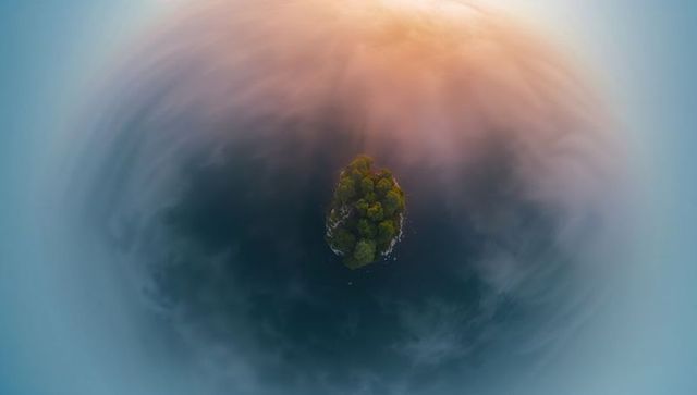 Encircling mist ring around remote evergreen islet at sunrise, aerial minimalist landscape