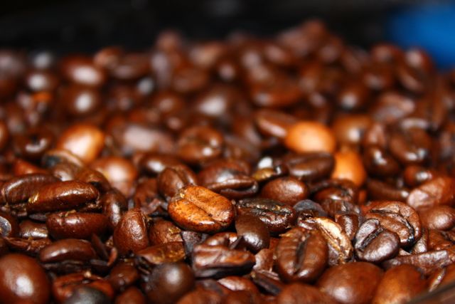 High-resolution macro shot of roasted coffee beans celebrating rich texture and dark tones. Ideal for use in coffee shop decor, product packaging, beverage advertisements, or blogs about coffee culture and brewing techniques.