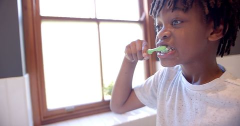 Young boy brushing teeth in bathroom promoting oral hygiene