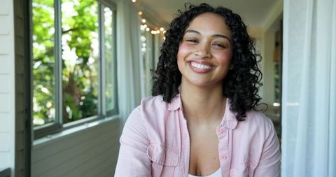 Smiling young woman relaxing indoors with natural light and greenery
