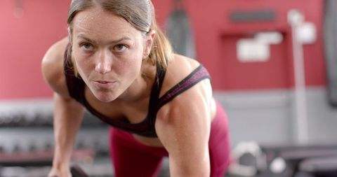 Focused female athlete lifting weights in gym setting