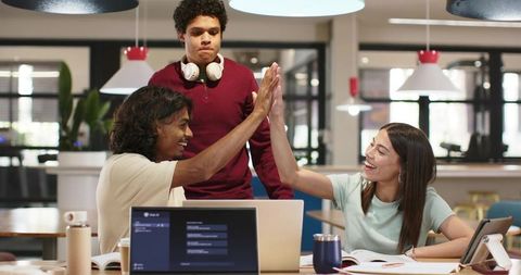 High-fiving coworkers celebrating project success in modern coworking space