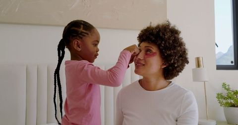 Bonding moment with daughter applying makeup to mother