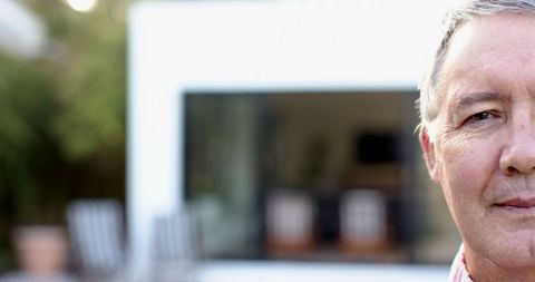 Senior Man Relaxing on Modern Outdoor Patio with Sliding Glass Door