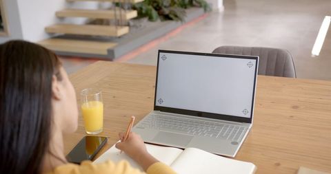 Woman Writing in Notepad: Laptop, Smartphone, Juice by Her Side: Home Workspace Vibe