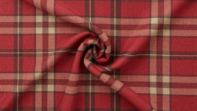 Twisting red tartan plaid fabric with radial folds and woven texture