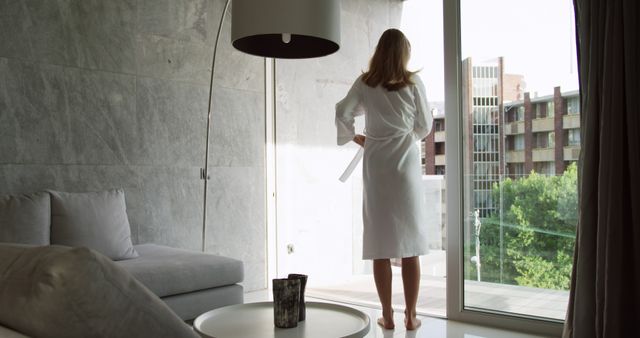 Serene Morning with Woman in Bathrobe Looking Out Balcony Window - Download Free Stock Images Pikwizard.com