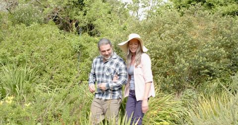 Happy Couple Walking Through Sunny Garden Path in Summer