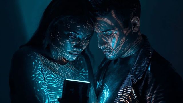 Couple Illuminated by Futuristic Light Projections Viewing Smartphone