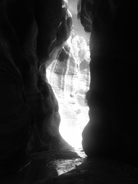 Scenic view of sunlight piercing through the narrow walls of a slot canyon, creating dramatic shadows and lighting. Ideal for use in nature, adventure, and geology publications, or as wall art for those appreciating natural landscapes and light contrasts.