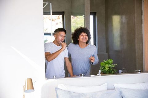 Happy Couple Brushing Teeth Together in Modern Bathroom